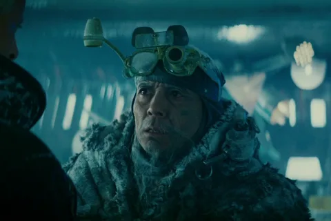 Chew in a frost-covered fur coat and magnifying goggles facing Roy Batty in his freezing eye lab in Blade Runner