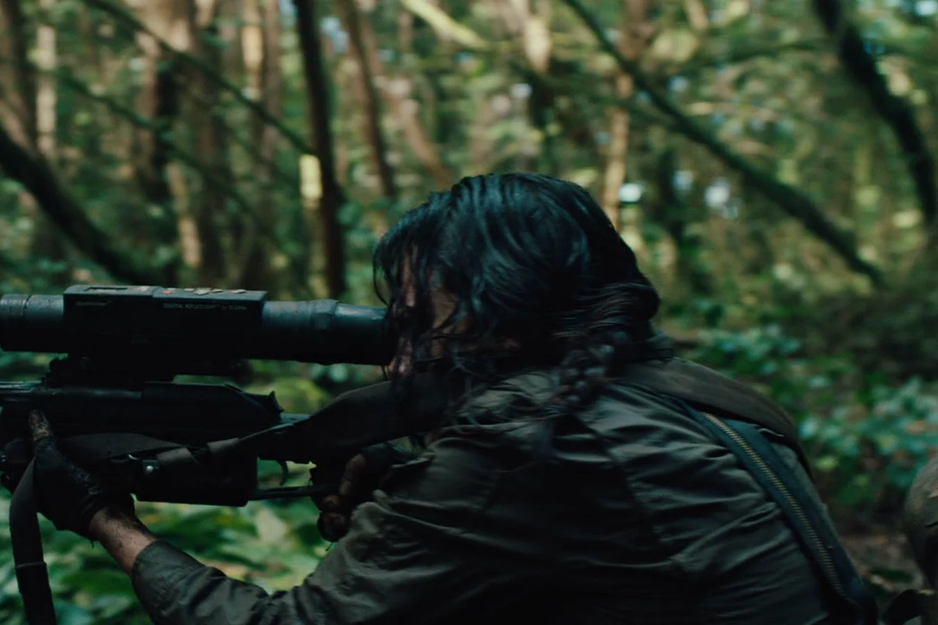 Isabelle sighting through the scope of her sniper rifle from cover in the jungle