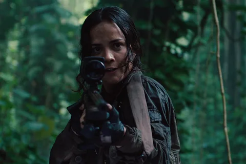 Isabelle aiming her scoped sniper rifle at the camera in a dense blue-green forest