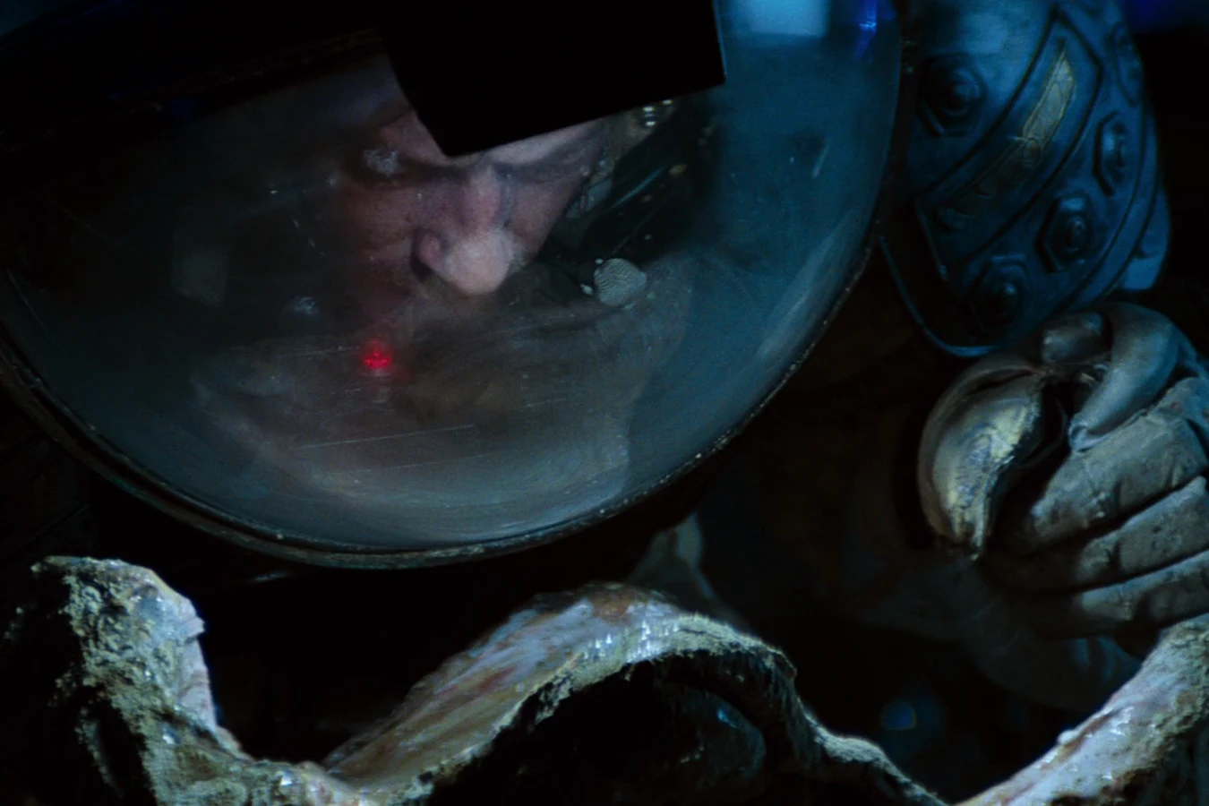 Kane in his helmet leans over an opening egg in the derelict