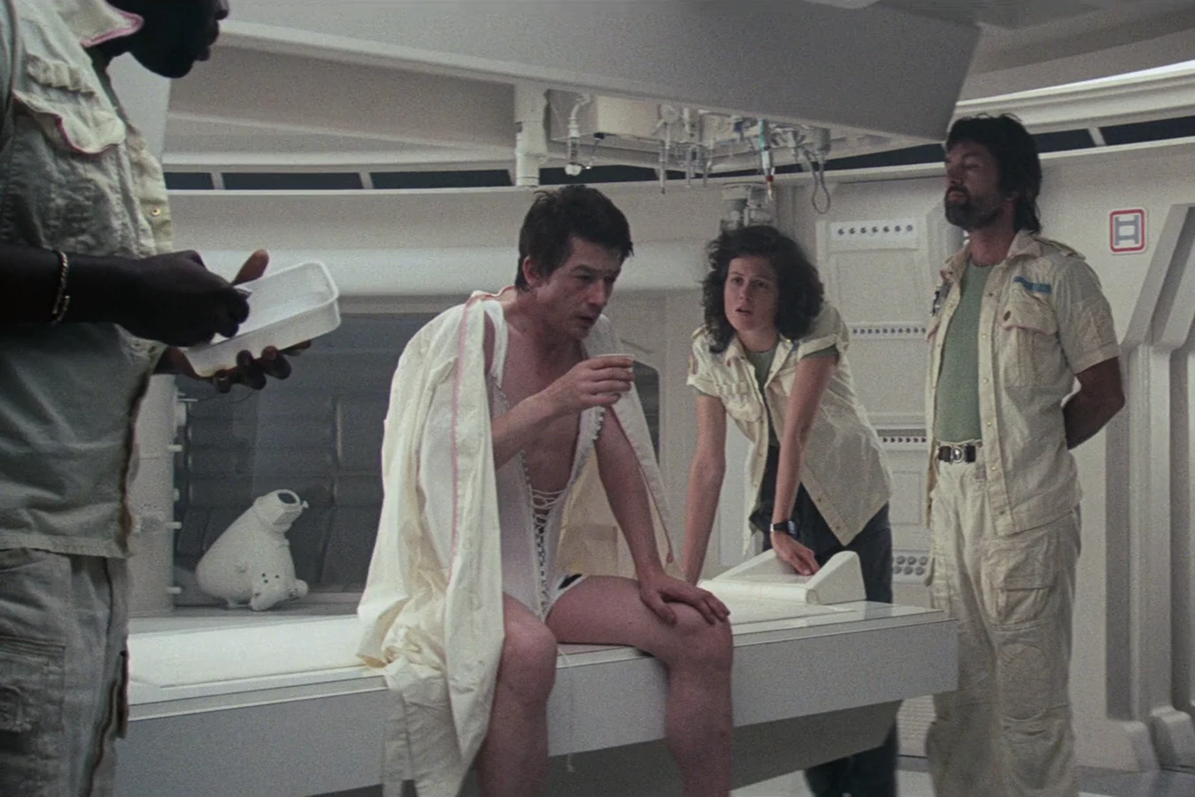Kane sits on the Nostromo infirmary table after the Facehugger dropped off