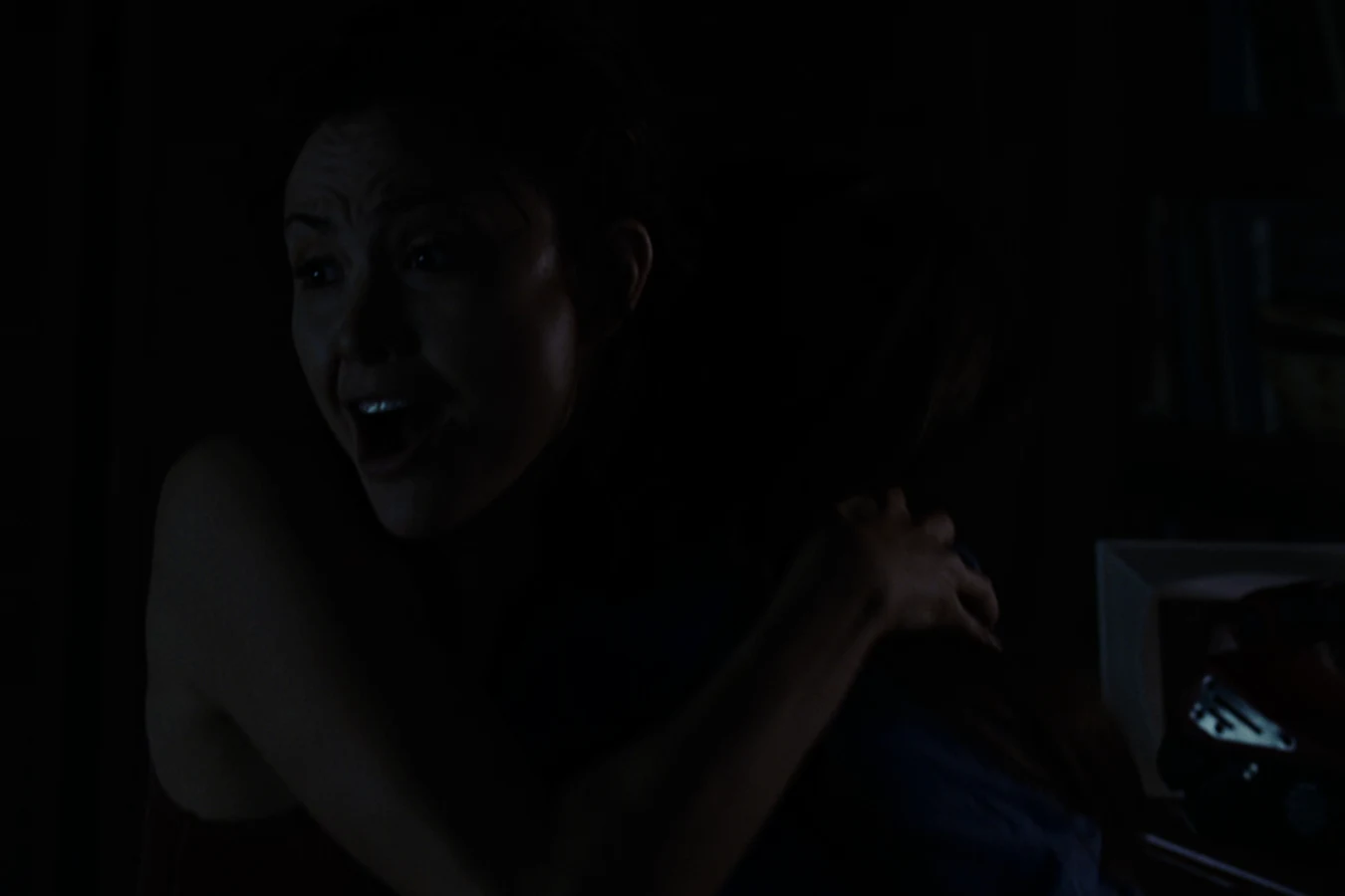 Close-up of Kelly O'Brien looking shocked in the dark after Molly reports a monster outside