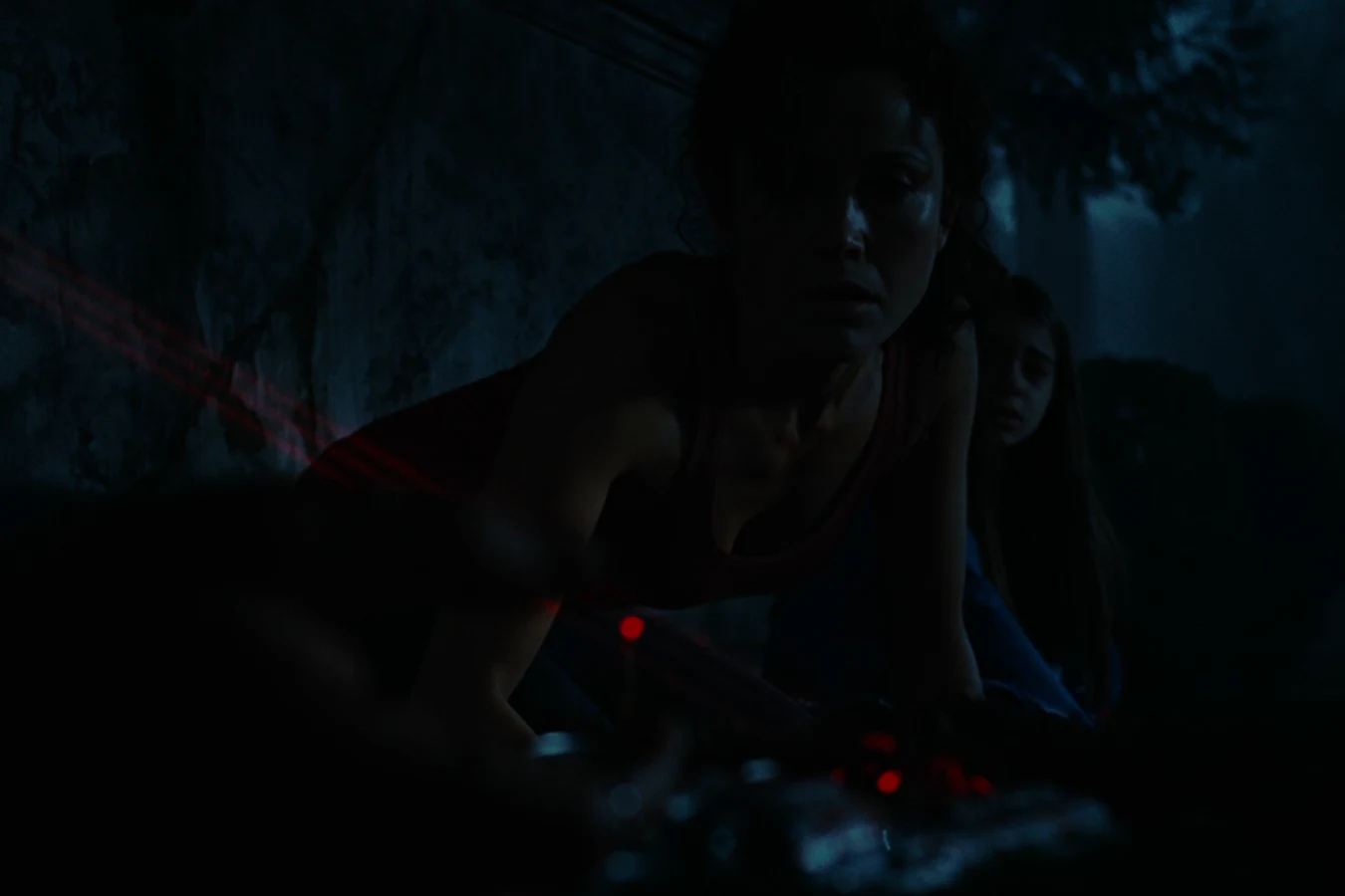 Kelly O'Brien crouches with Molly behind her in a dark cemetery as red targeting lasers cut across the ground