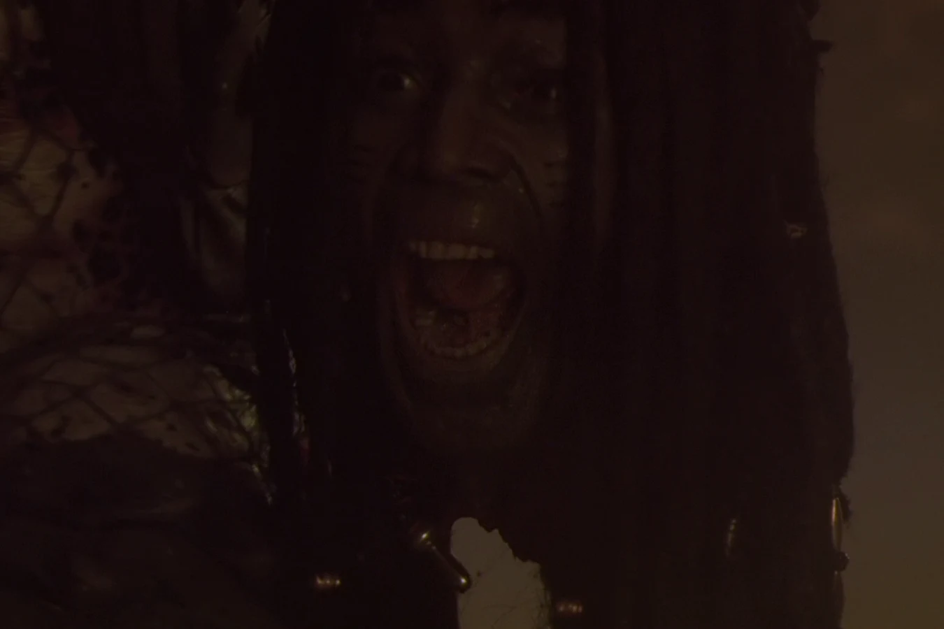 The City Hunter holds King Willie's severed head after killing him in the alley in Predator 2