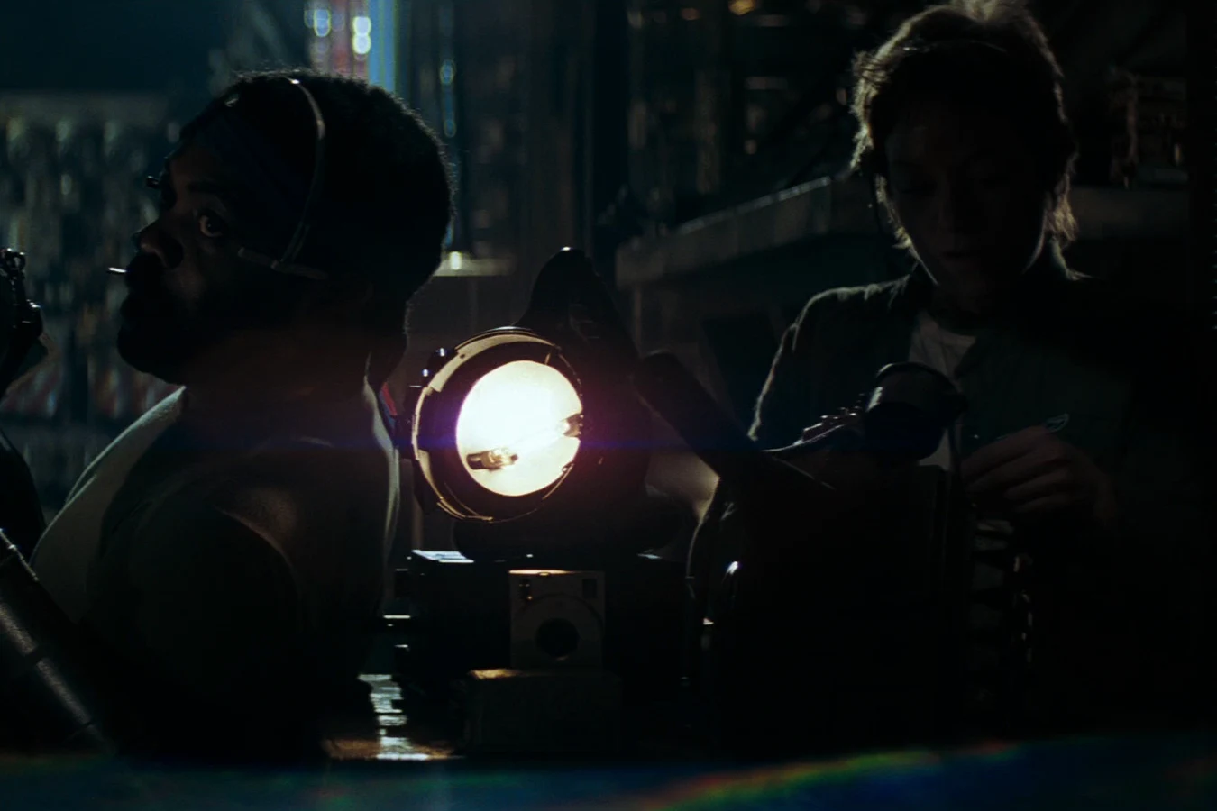 Lambert works beside Parker and a work light while they rig gear on the Nostromo