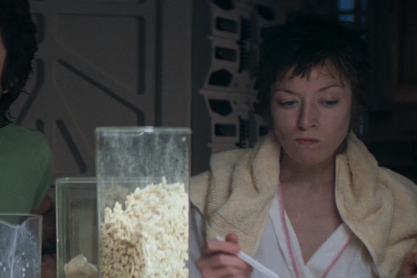 Lambert eats breakfast in the Nostromo mess with a towel over her shoulders in Alien