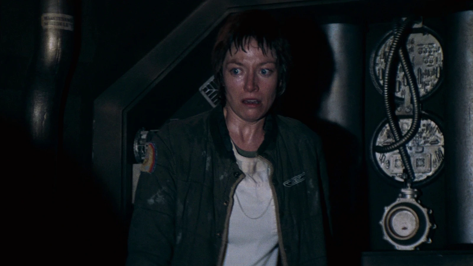 Lambert in a green jacket stands in a Nostromo corridor in Alien