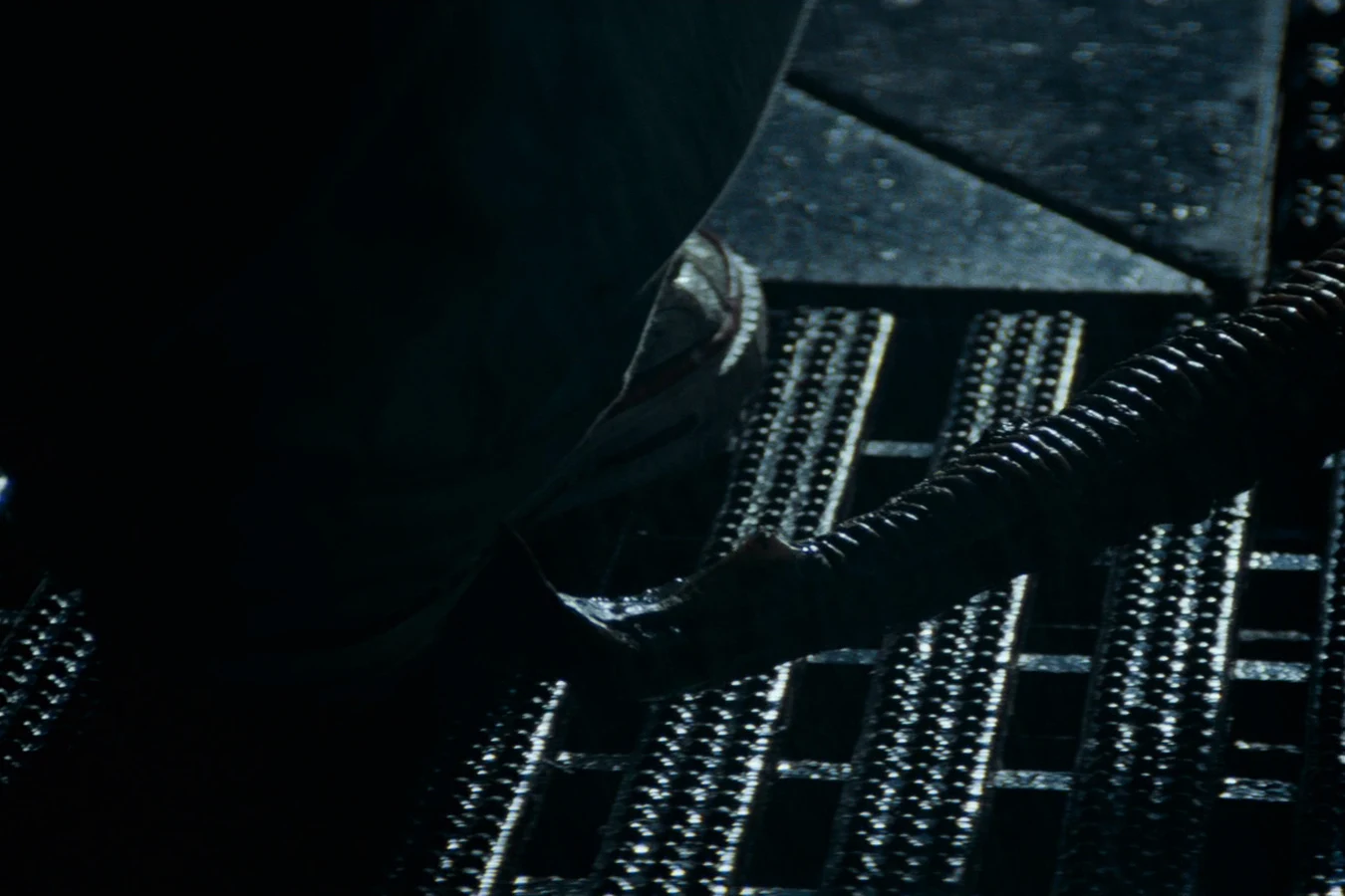 The adult Xenomorph's tail rises between Lambert's legs on the Nostromo grating in Alien