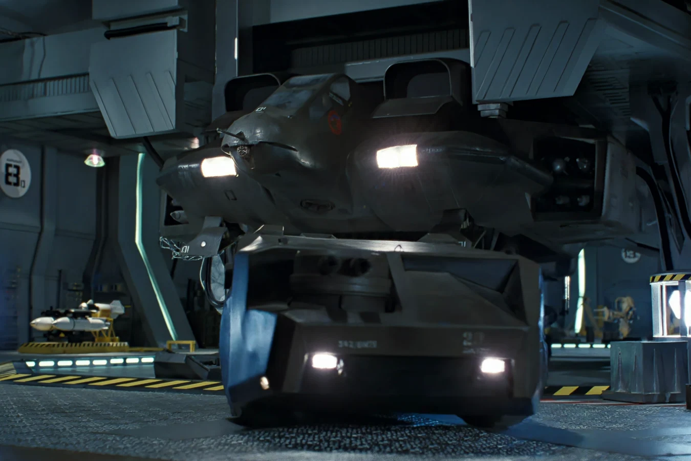 The M577 APC in a Sulaco hangar in Aliens, headlights on, with a UD-4 Cheyenne dropship parked behind it