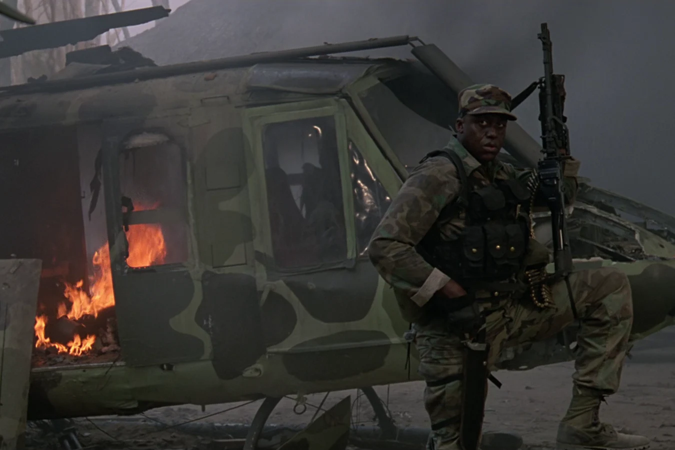 Mac Eliot with his M60 at the burning helicopter wreck in Predator