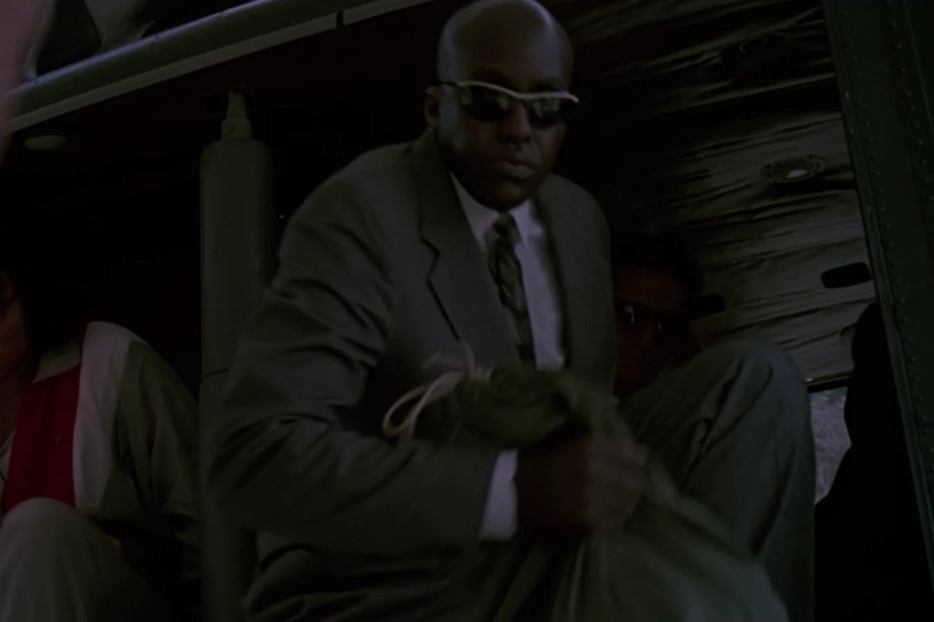 Mac Eliot in a civilian suit and sunglasses arriving with Dutch's team in Predator