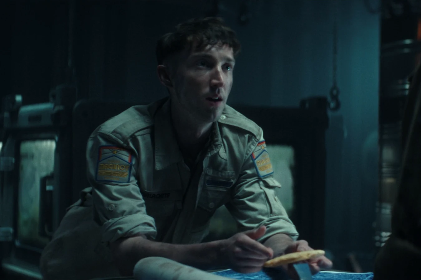 Malachite seated in a dim Maginot compartment holding a cracker in Alien: Earth