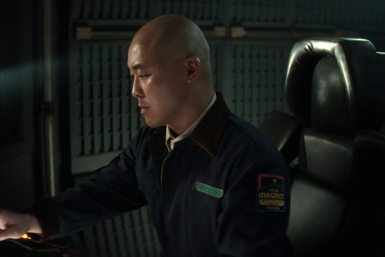 Teng leaning over a console in his Maginot navigator uniform in Alien: Earth