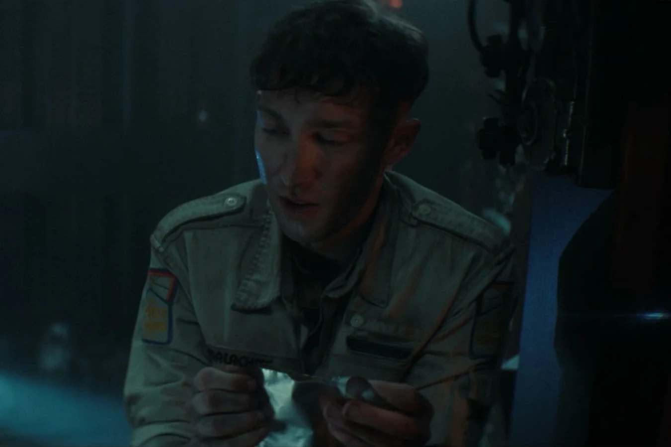 Malachite in his Maginot jumpsuit looking down at a foil pack in Alien: Earth
