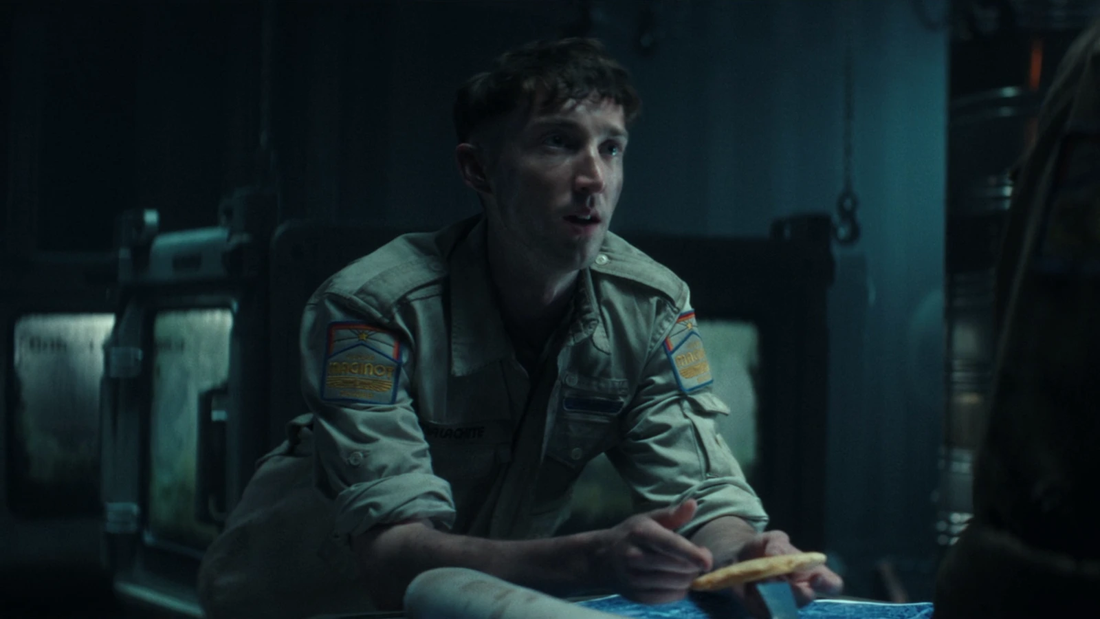 Malachite seated in a dim Maginot compartment holding a cracker in Alien: Earth