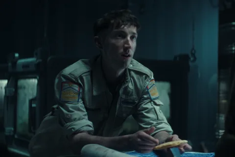 Malachite seated in a dim Maginot compartment holding a cracker in Alien: Earth