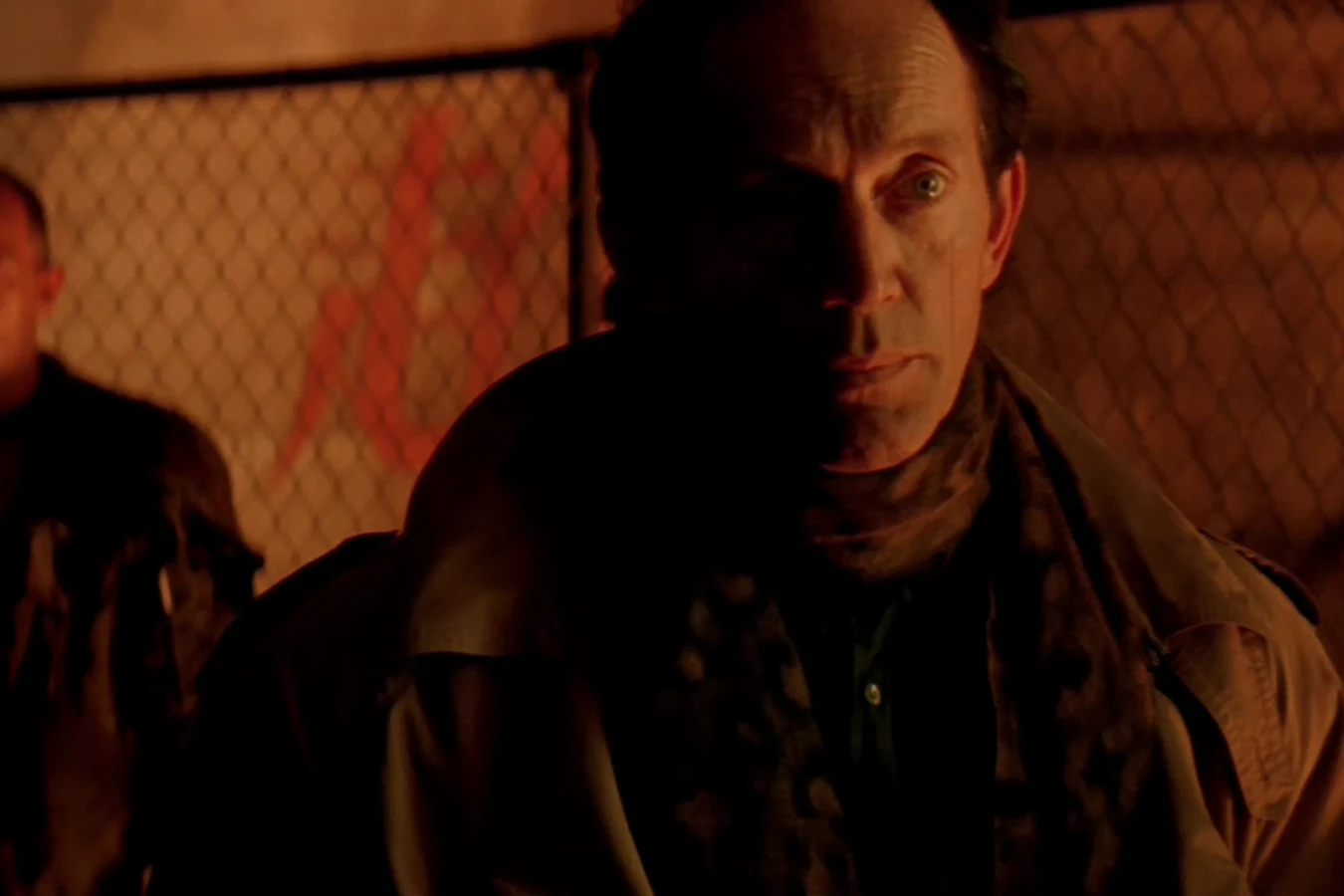 Michael Bishop in a coat and scarf on Fury 161, standing in front of a fence