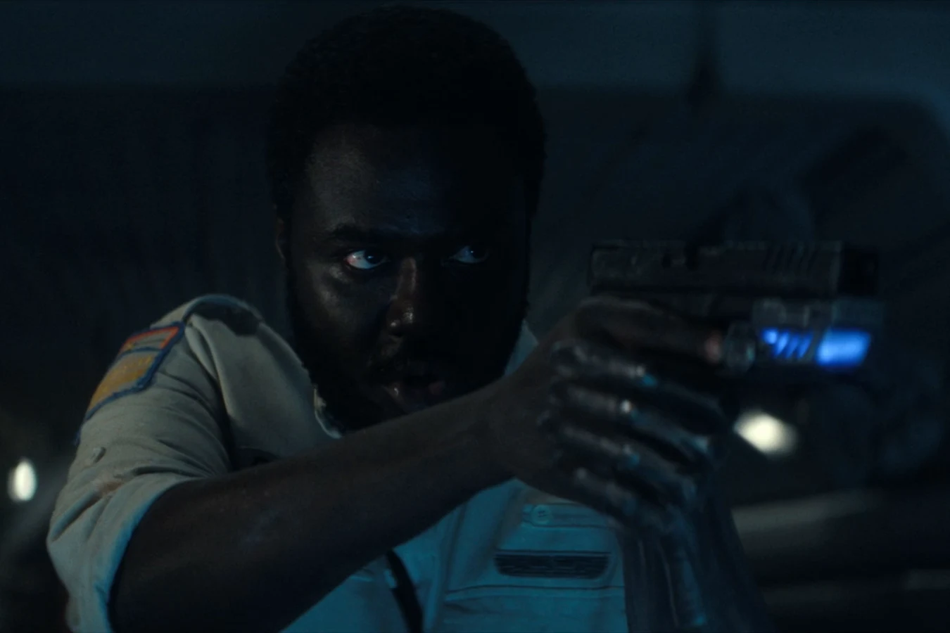 Morrow aiming a pistol inside the wrecked Maginot specimen lab after the crash in Alien: Earth