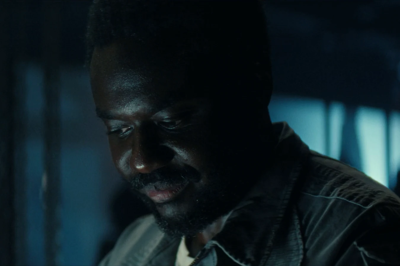 Morrow lit by blue light as he speaks to Slightly over a hidden transmitter in Alien: Earth