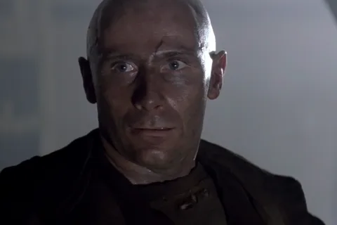 Morse staring ahead in a dark prison coat in Alien 3