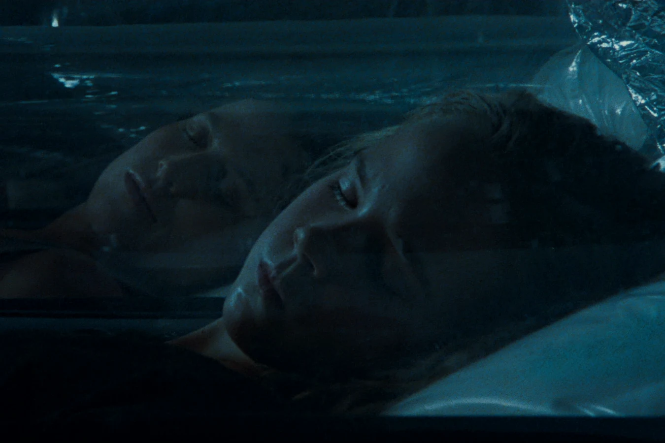 Newt asleep in a Sulaco cryotube with her reflection on the glass in Aliens