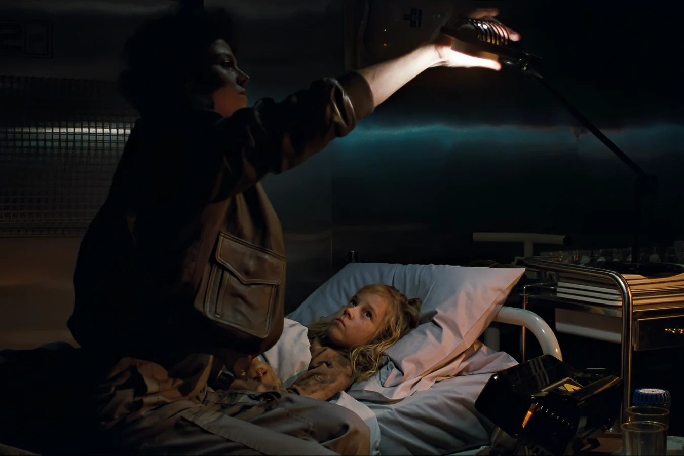 Ripley turning on a lamp while Newt lies in a Hadley's Hope medlab bed in Aliens