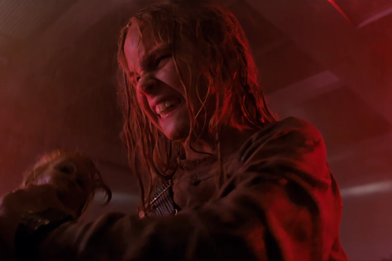 Newt holding Casey under red emergency lights as Facehuggers attack the medlab in Aliens