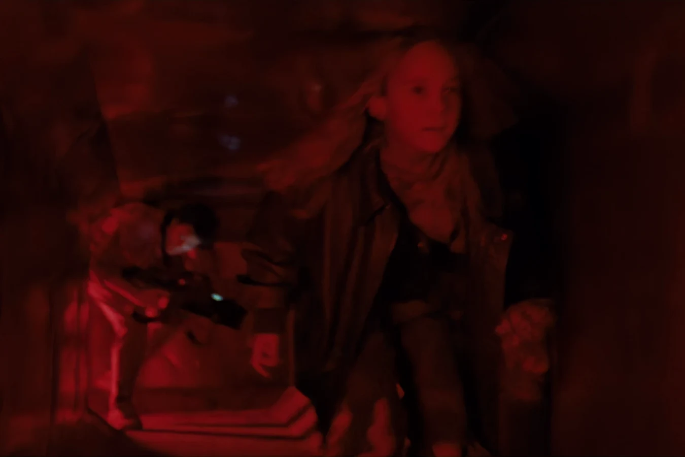 Newt running through a red-lit Hadley's Hope corridor with Bishop behind her in Aliens