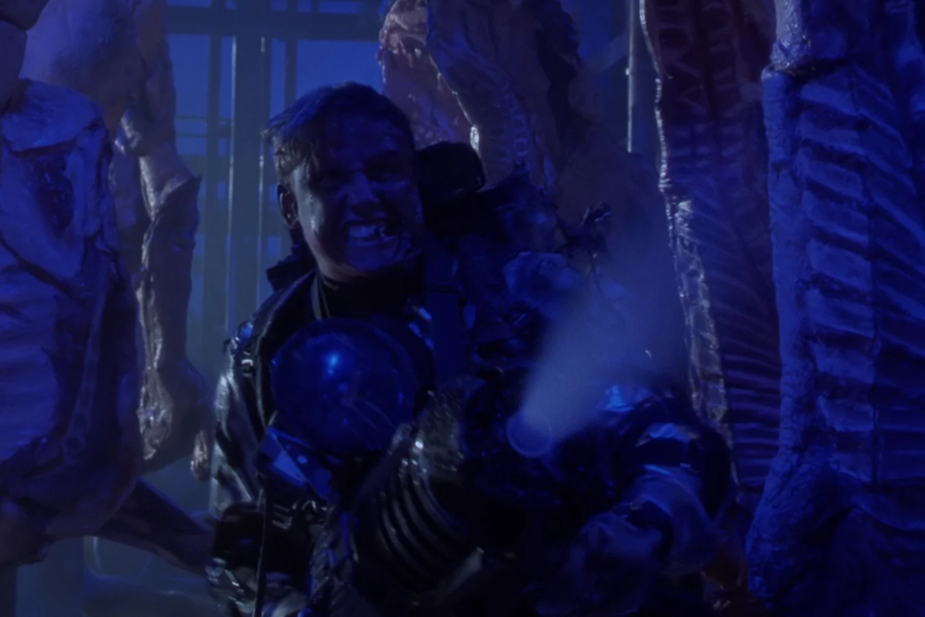 Peter Keyes aims a nitrogen gun among hanging carcasses in Predator 2
