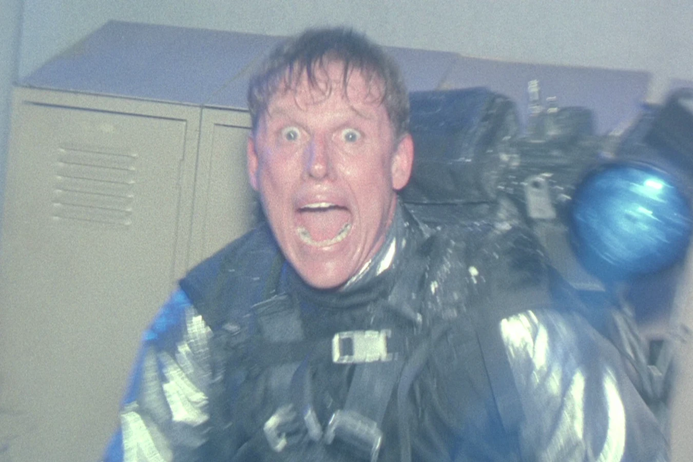 Peter Keyes recoils in a refrigerated suit after a wrist rocket hit in Predator 2