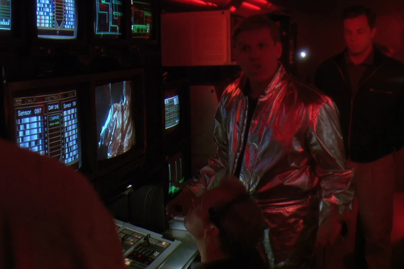Peter Keyes in a silver refrigerated suit at the OWLF trailer monitors in Predator 2