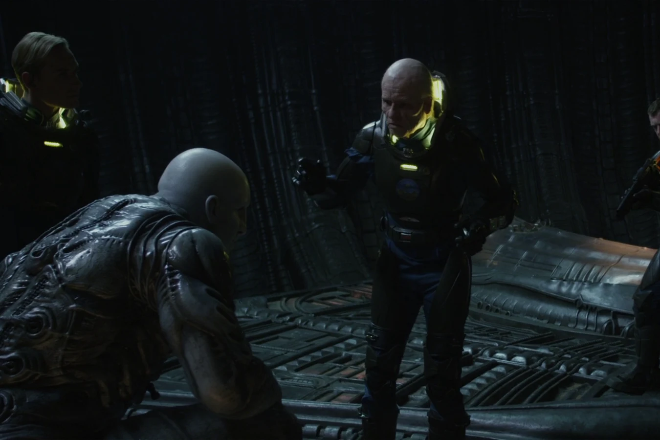 The Engineer on the deck of the buried ship while Peter Weyland stands over him in a lit suit