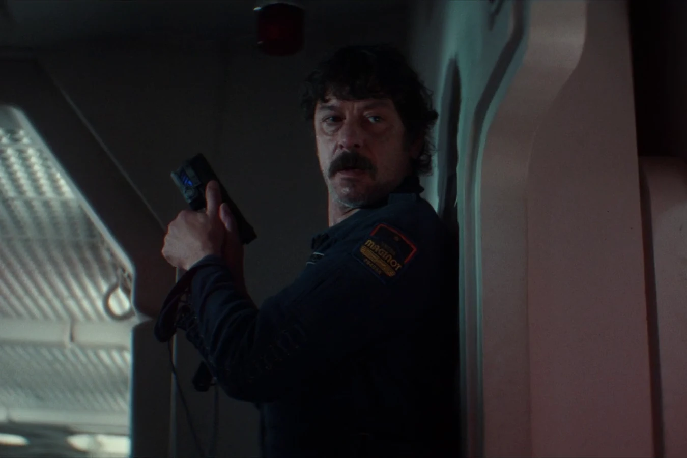 Petrovich hiding against a Maginot corridor wall with a pistol before his confrontation with Morrow in Alien: Earth