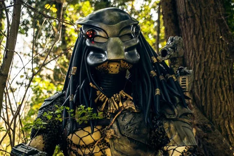 A Predator cosplayer in a full Yautja suit