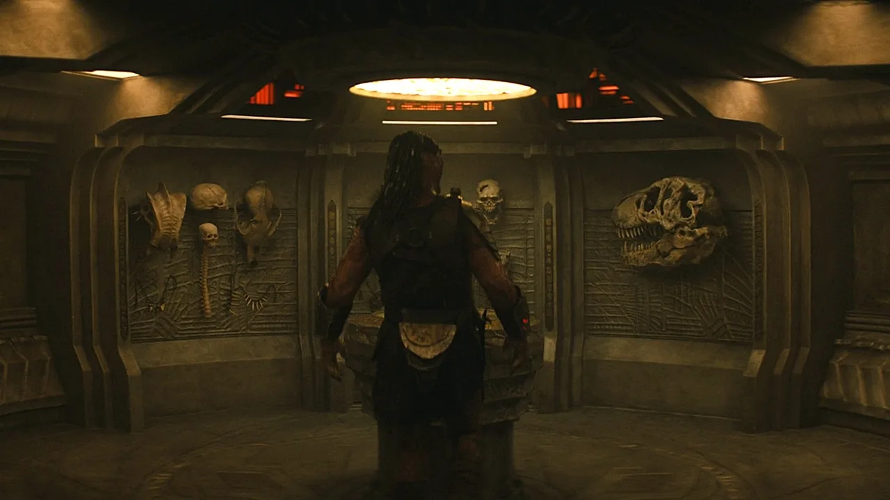 Dek Predator standing in front of a trophy wall aboard Kwei's ship in Predator: Badlands