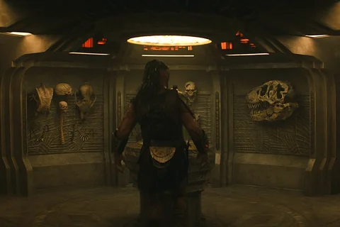 Dek Predator standing in front of a trophy wall aboard Kwei's ship in Predator: Badlands