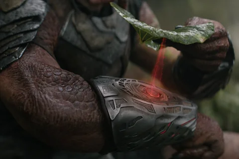Dek Predator scanning a leaf with his wrist gauntlet from Predator: Badlands
