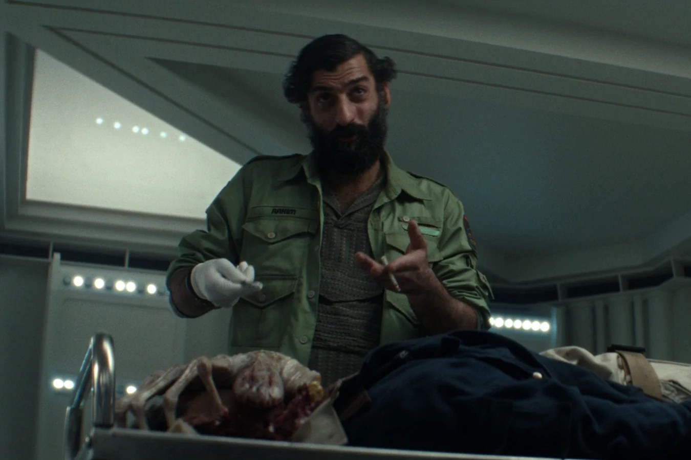 A Maginot crew member standing over Captain RJ Dinsdale's body and the dead Facehugger in the medbay in Alien: Earth