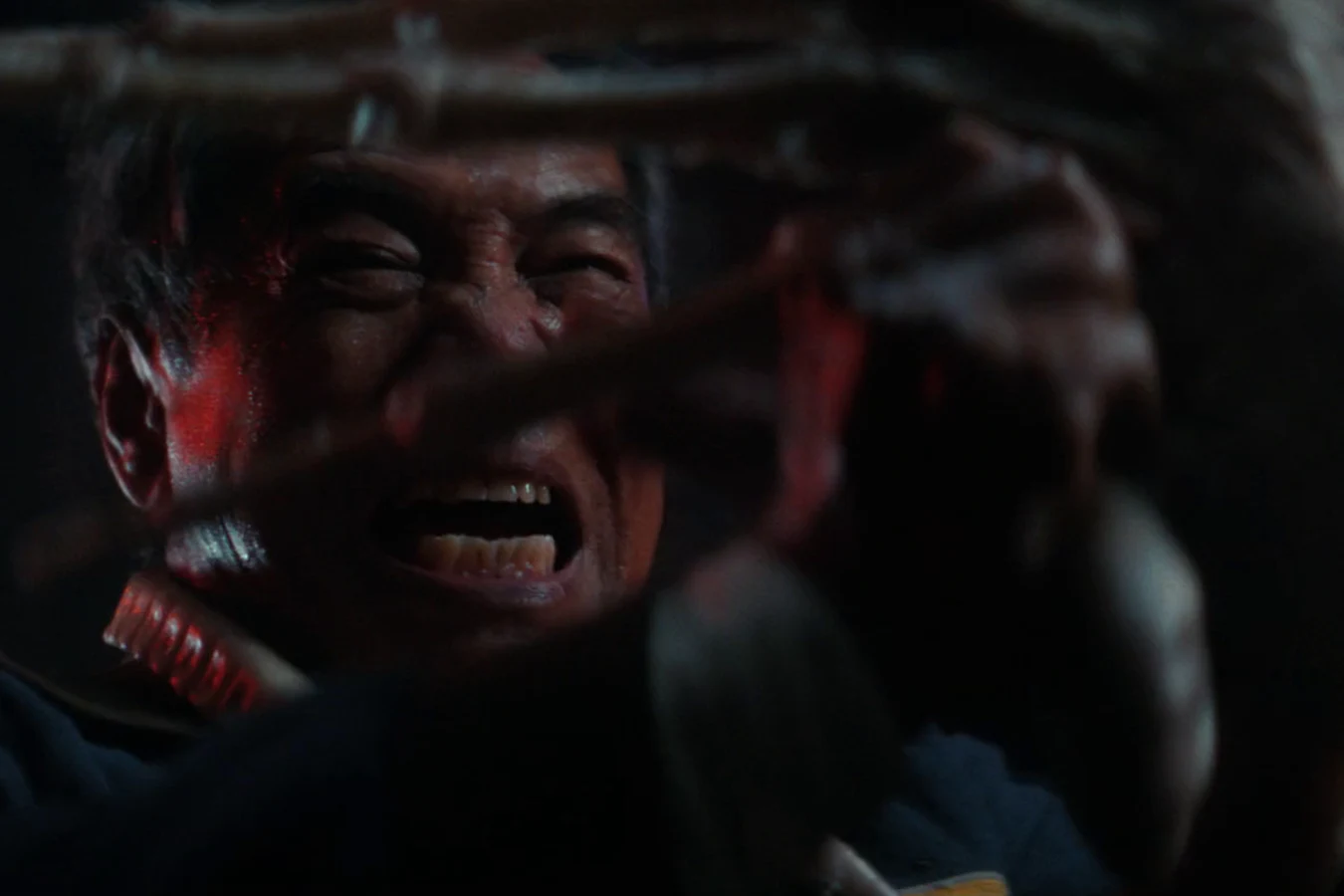A Facehugger clamped over Captain RJ Dinsdale's face in the red-lit containment room aboard the Maginot in Alien: Earth