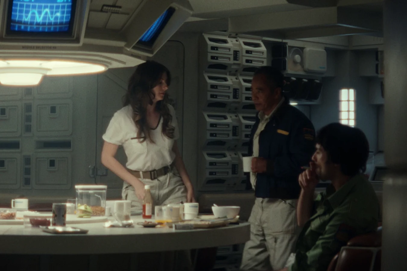 Captain RJ Dinsdale holding a mug beside the galley table as crew members gather in the Maginot mess hall in Alien: Earth