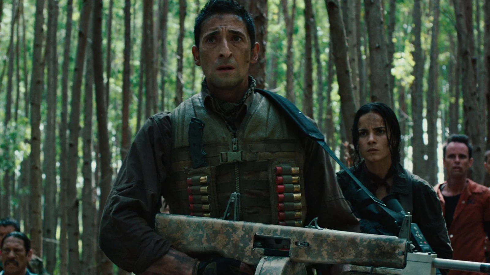 Royce holding his AA-12 shotgun in a forest of tall thin trees, with Isabelle behind him