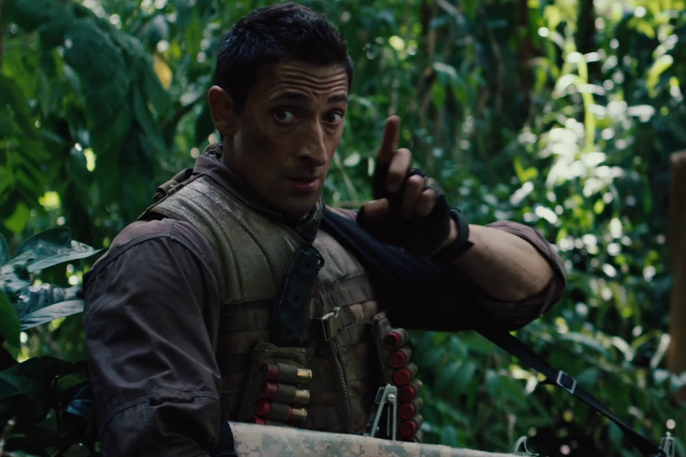 Royce raising one hand to signal the group while holding his AA-12 shotgun in the jungle