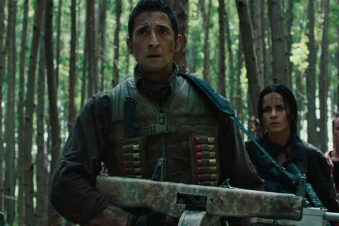 Royce holding his AA-12 shotgun in a forest of tall thin trees, with Isabelle behind him