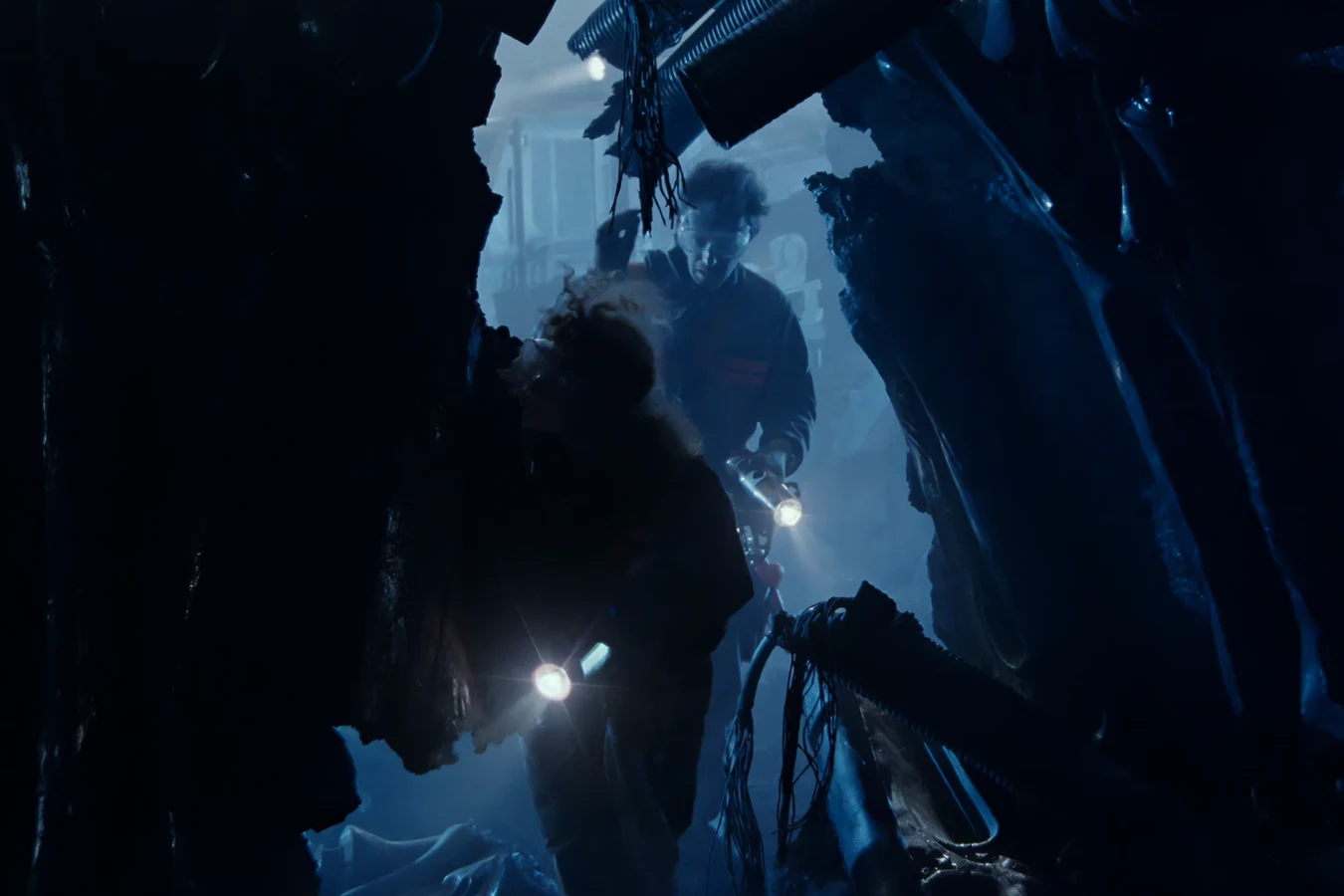 Russ and Anne Jorden with flashlights making their way into the dark, broken hull of the derelict ship on LV-426