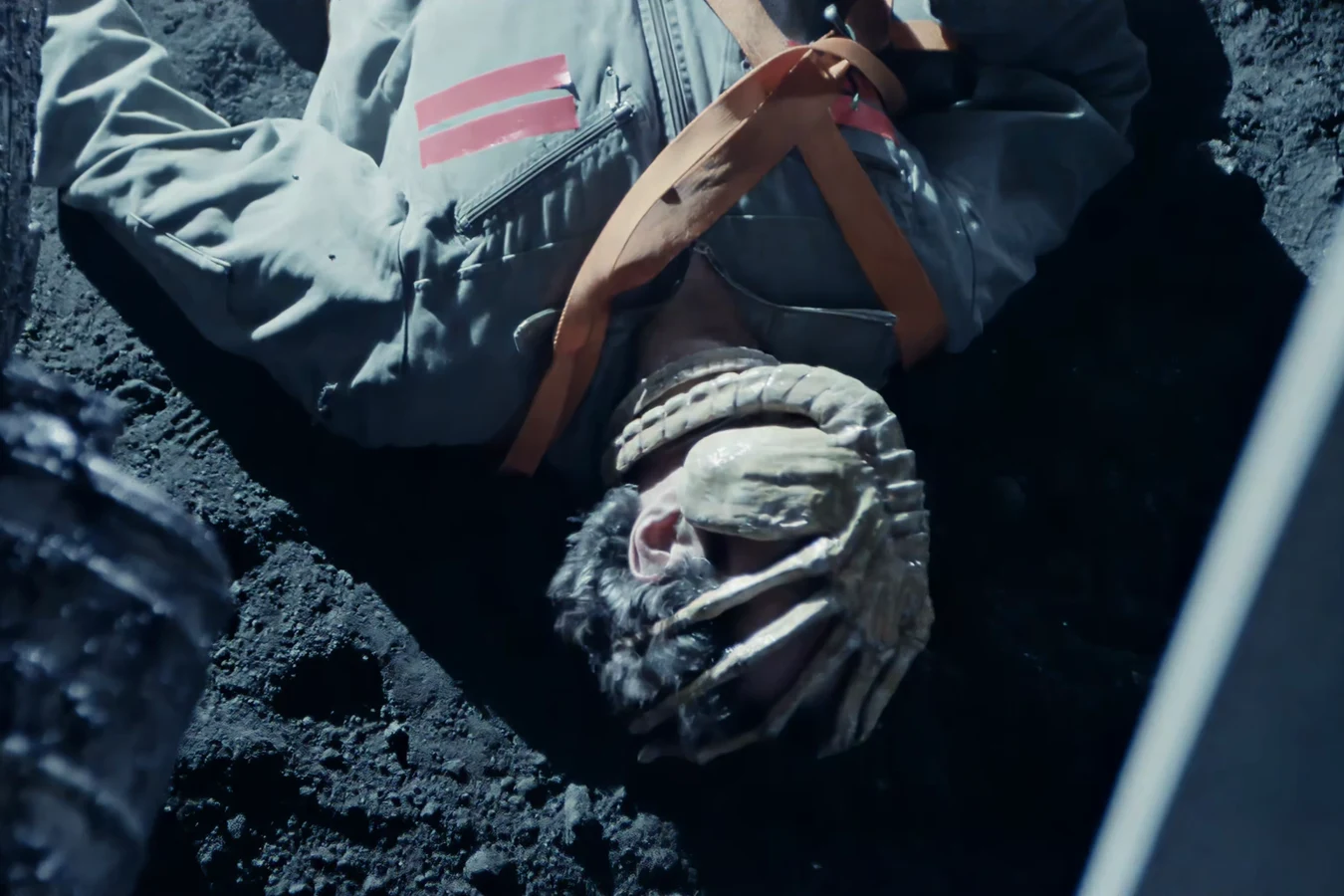 Russ Jorden lying in the dark volcanic dirt of LV-426 with a Facehugger clamped over his face in the Aliens Special Edition