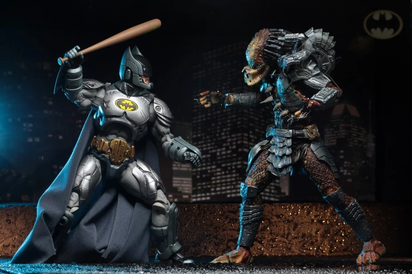 NECA armored Batman with a baseball bat facing the Batman vs. Predator Predator figure on a Gotham rooftop backdrop