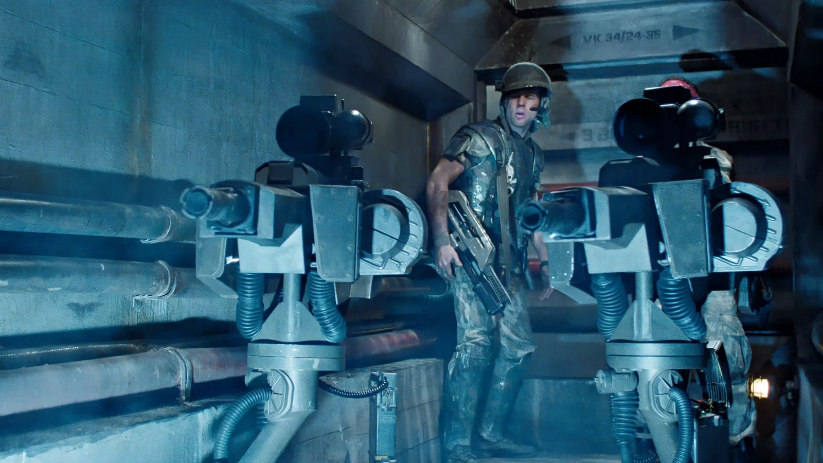 Hudson standing between two UA 571-C Automated Sentry Guns in a Hadley's Hope corridor