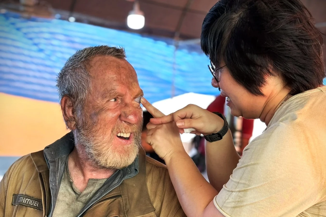 Behind the scenes photo of Michael Smiley in Shmuel costume and makeup having his eye area touched up for Alien: Earth