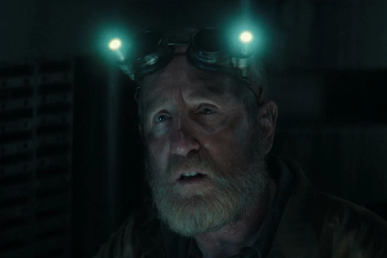 Close-up of Shmuel with lit headlamp goggles in the dark Maginot engine bay in Alien: Earth