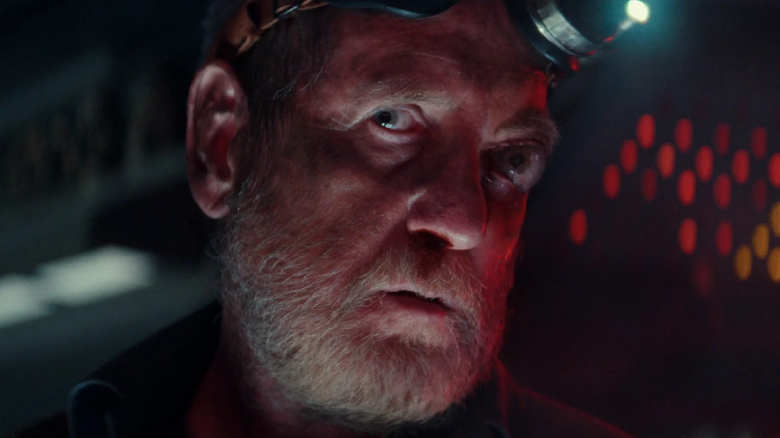 Close-up of Shmuel lit in red with a headlamp on his brow aboard the Maginot in Alien: Earth